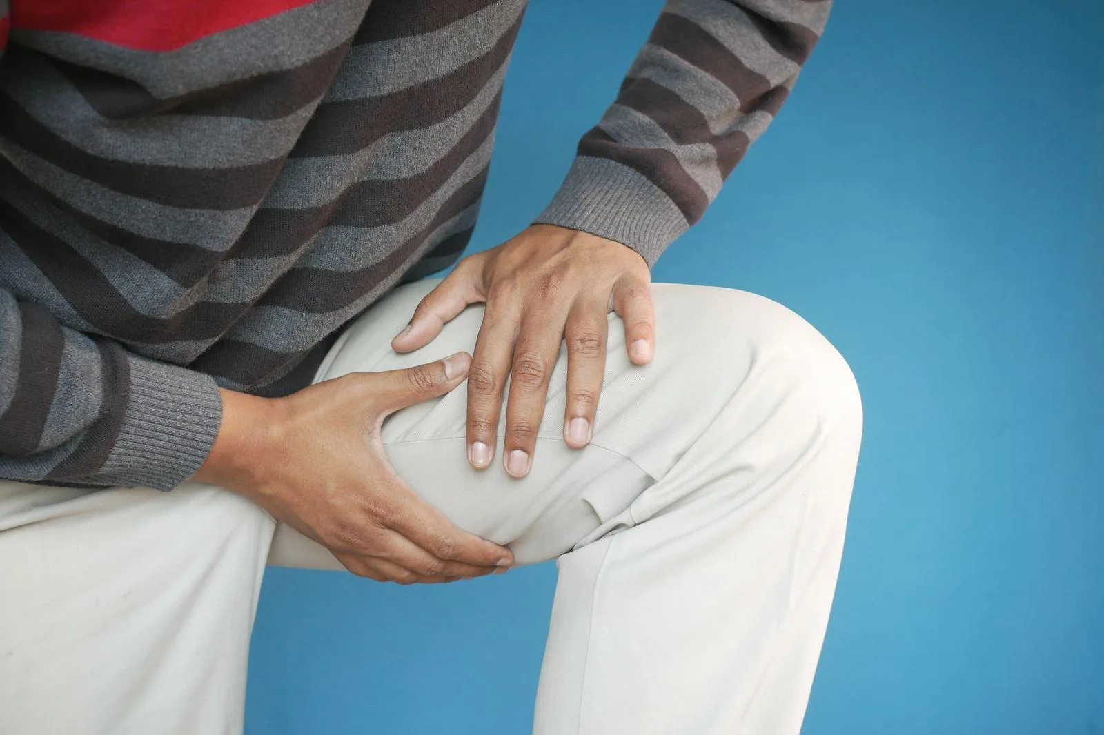 A person gripping the front of a painful knee